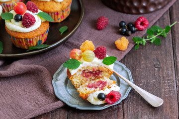 Cupcakes with butter cream and raspberry curd, decorated with berries on a wooden surface.
