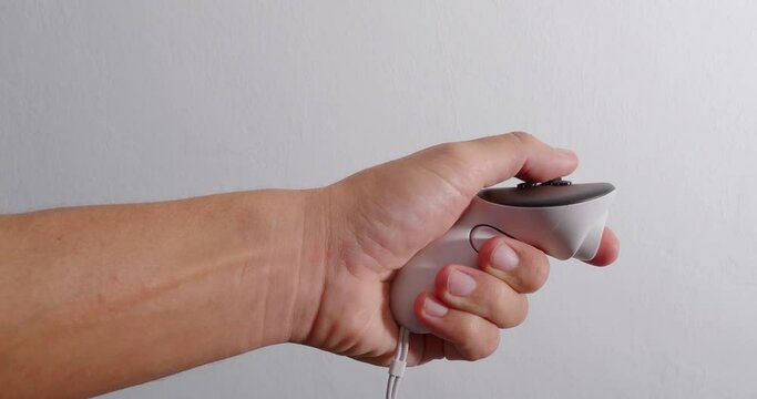 Hand holding white controller playing game.