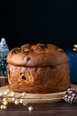 Panettone con chispas de chocolate para regalar en un fondo con ambiente festivo oscuro con detalle, plato típico italiano