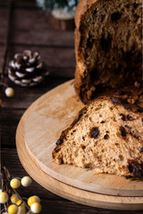 Panettone con chispas de chocolate para regalar en un fondo con ambiente festivo oscuro, plato típico italiano con corte para servir