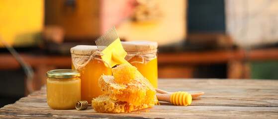 Jars of sweet honey and combs on table at apiary - obrazy, fototapety, plakaty