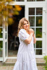 an attractive woman in a white summer dress on the threshold of a country house