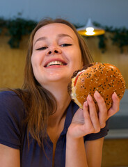 Portrait of young happy woman or beautiful teenager girl eating fast junk food, tasty burger and...