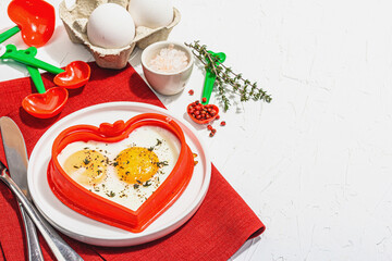 Heart-shaped fried egg served with toasted bread. Romantic art food idea for Valentine's breakfast