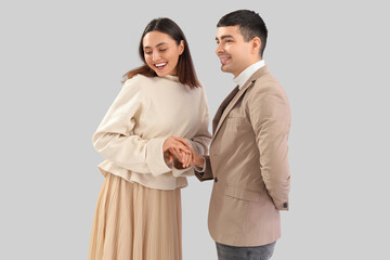 Lovely young couple holding hands on light background
