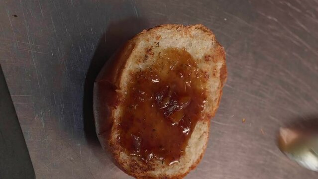Chef in black gloves making burge. spread sauce on bun. Close-up of a skilled craftsman working at the workplace 