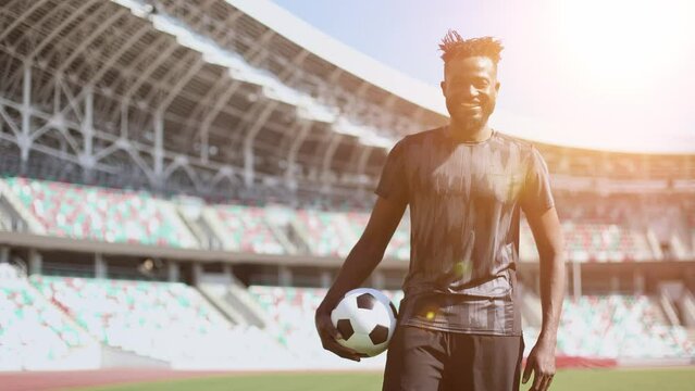 afro american football player in a gray t-shirt holding the ball in his hand