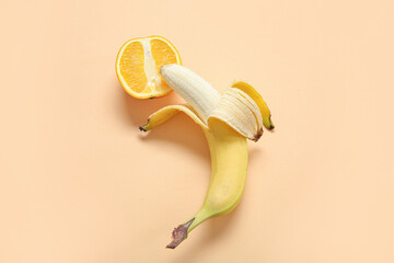 Fresh banana with orange on beige background. Sex education concept