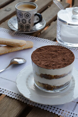 Tiramisu on a cup with a coffee in the background