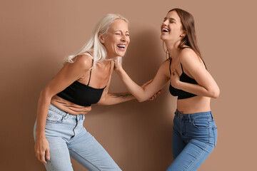 Body positive women laughing on beige background