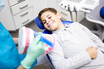 Teach kids how to brush their teeth! An unrecognizable dentist is teaching oral hygiene lessons to a child with a toy set of teeth. Use the toothbrush properly.