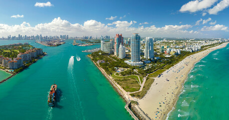 View from above of big container ship entering main channel in Miami harbor near South Beach high luxurious hotels and apartment buildings - obrazy, fototapety, plakaty