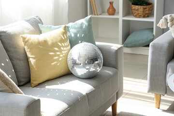 Disco ball on grey sofa in interior of modern living room