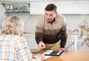 Male financial agent tells an elderly woman the terms of microloan. Offers to sign documents