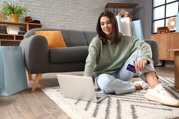 Young woman with laptop and credit card shopping online at home