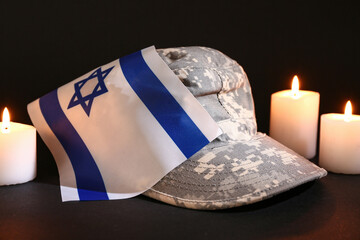 Military cap with flag of Israel and burning candles on dark background