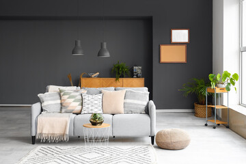 Interior of modern living room with cozy grey sofa, pouf and coffee table