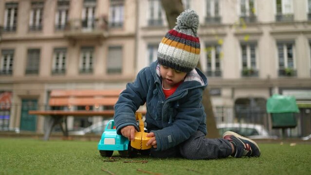 Child Playing with Truck claw at Park in Autumn, wearing beanie and jacket during cold season while immersed in play