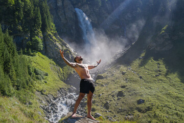 Obraz premium Man in Alps waterfall. Sexy man. Man freedom lifestyle. Meditating in nature. Hispanic man practicing yoga. Lifestyle relaxation concept, summer meditation on nature. Calmness and relax in nature.