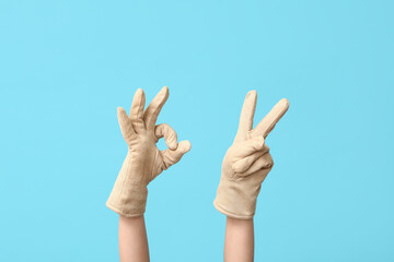 Hands in warm gloves gesturing on blue background