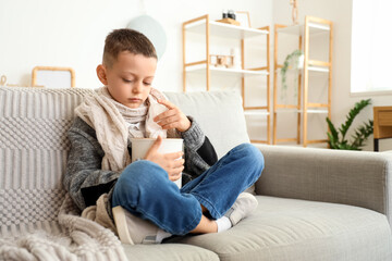 Ill little boy taking tissue from box on sofa at home