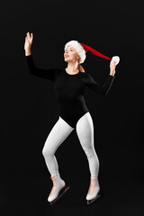 Beautiful female figure skater in ice skates and Santa hat on black background