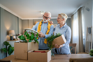 Senior couple man and woman husband wife pack or unpack boxes moving - Powered by Adobe