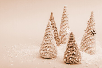 Handmade winter composition. Set of crocheted Christmas trees, artificial snow on pink background