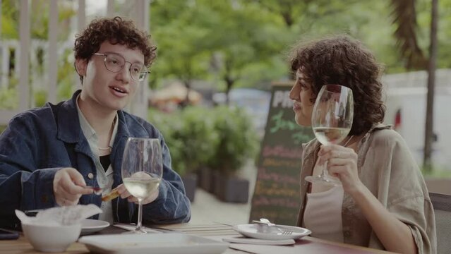 Casal de mulheres comendo e se divertindo durante agradavel almoco em um restaurante ao ar livre. Cinematico 4k.