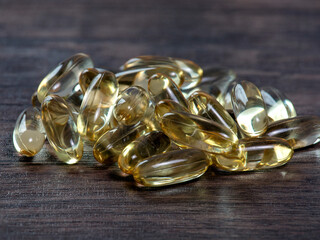 Closeup of fish oil yellow capsules on wooden background, vitamin D supplement, Omega 3.