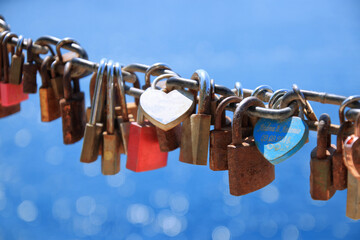 Love, romantic, dating in online internet website. Old rusty love locks on chain against background of blue sea on sunny day. Valentine day love symbol concept. Locked locks of love and loyalty.   - obrazy, fototapety, plakaty