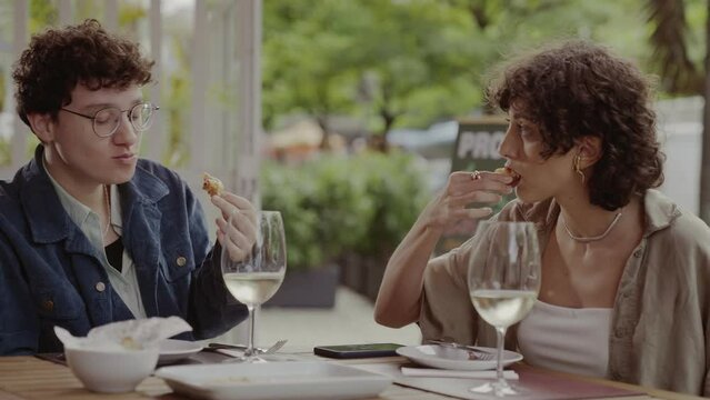 Casal de mulheres comendo e se divertindo durante agradavel almoco em um restaurante ao ar livre. Cinematico 4k.