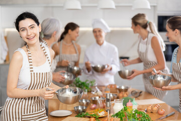 Girl while studying at culinary workshop school, cooks appetizing sauce, marinade, dough in bowl.
