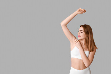 Beautiful young woman after depilation armpit on grey background