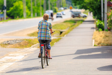 A cyclist in the village, viewed from the back. Background with selective focus and copy space
