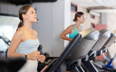 Fototapeta na wymiar Sporty woman doing cardio workout running on treadmill at fitness center