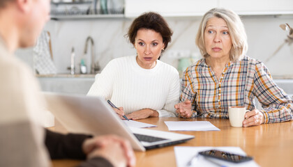 Obraz premium Mother and daughter considering offer from agent, asking questions and signing papers