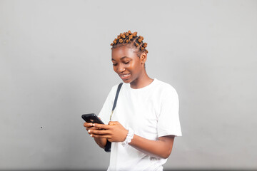 beautiful young african lady excited and rejoices while looking at her phone