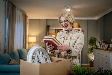 Senior woman caucasian female pack or unpack boxes with stuff moving