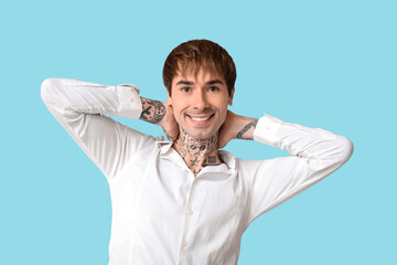 Happy handsome young tattooed man on blue background