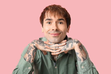 Happy handsome young tattooed man on pink background