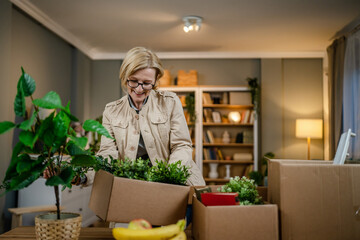 Senior woman caucasian female pack or unpack boxes with stuff moving