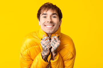 Happy handsome young tattooed man on yellow background