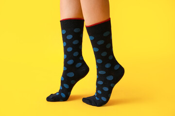 Legs of young woman in black dotted socks on yellow background