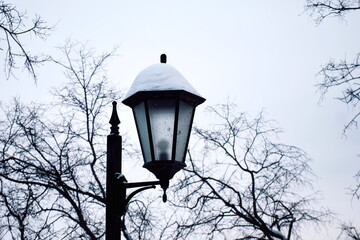 Fototapeta na wymiar Lantern on the street in winter. Retro style street lamp covered with snow during the day