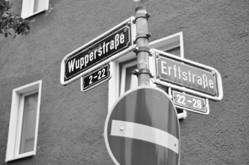 Greyscale shot of street signs indicating the intersection of Wupperstrasse and Erftstrasse streets