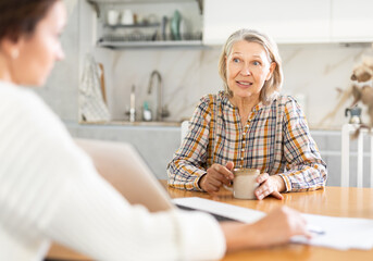 Real estate agent consulting elderly woman in home interior