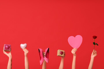 Female hands with beautiful rose, high heels and gift boxes on red background. Valentine's Day celebration