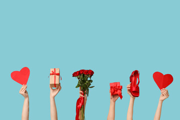 Female hands with bouquet of roses, paper hearts and gift boxes on blue background. Valentine's Day...