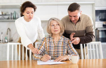 Old woman deciding and signing inheritance papers in family circle
